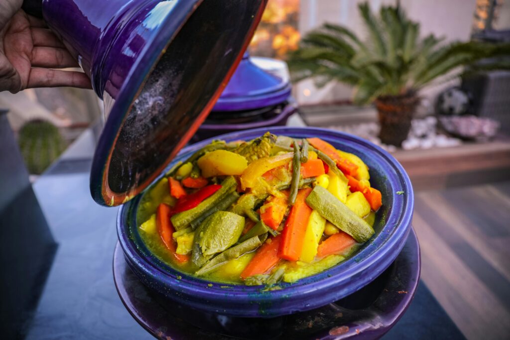 Delicioso tajín de verduras, lleno de color y sabor, presentado en un tradicional tajine morado con ingredientes frescos y aromáticos.
