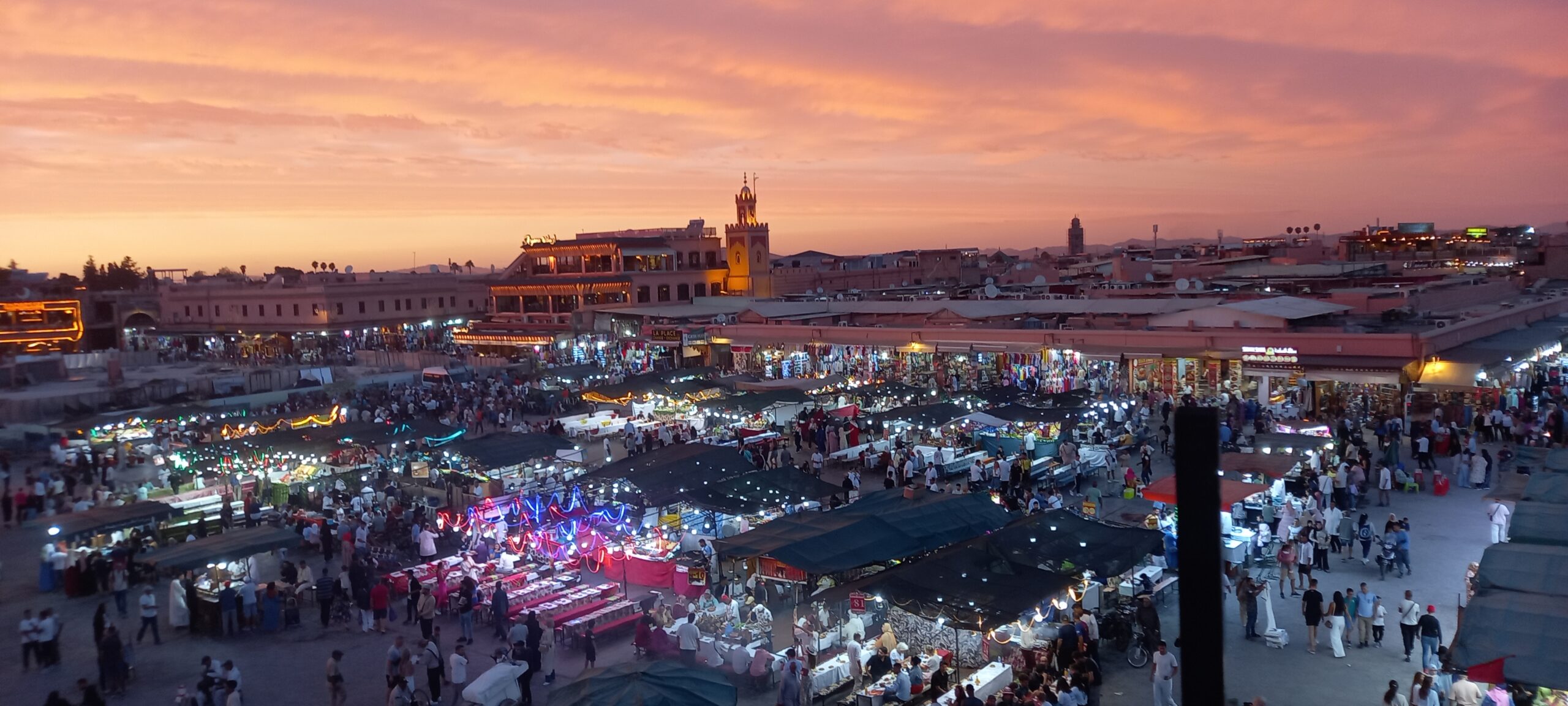Vista panorámica de la Plaza Jemaa el-Fna en Marrakech al atardecer, con la actividad de los puestos de comida, un punto culminante de los viajes.
